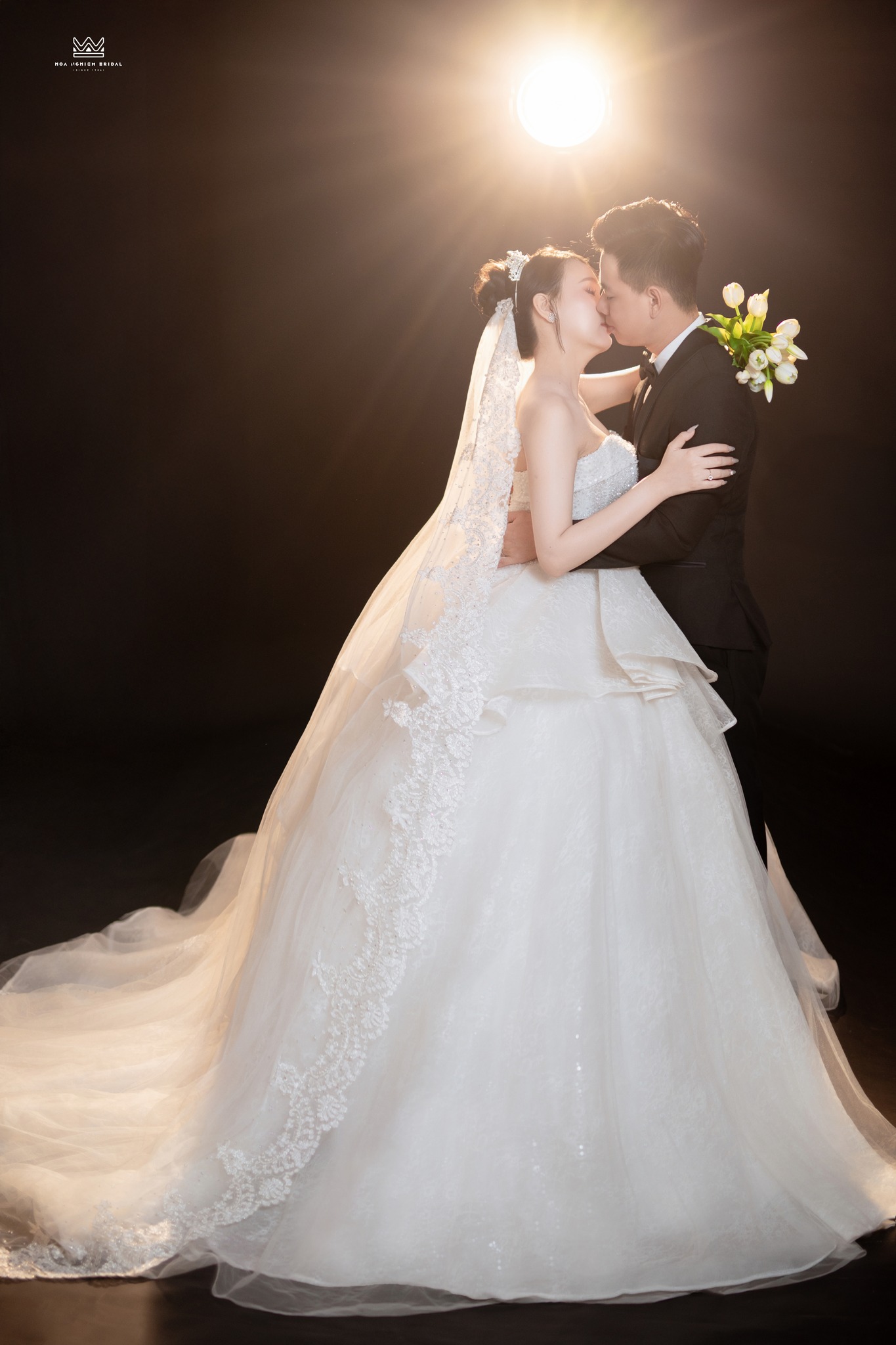 Ảnh cưới studio backlight cô dâu chú rể hôn nhau dưới ánh sáng vàng
