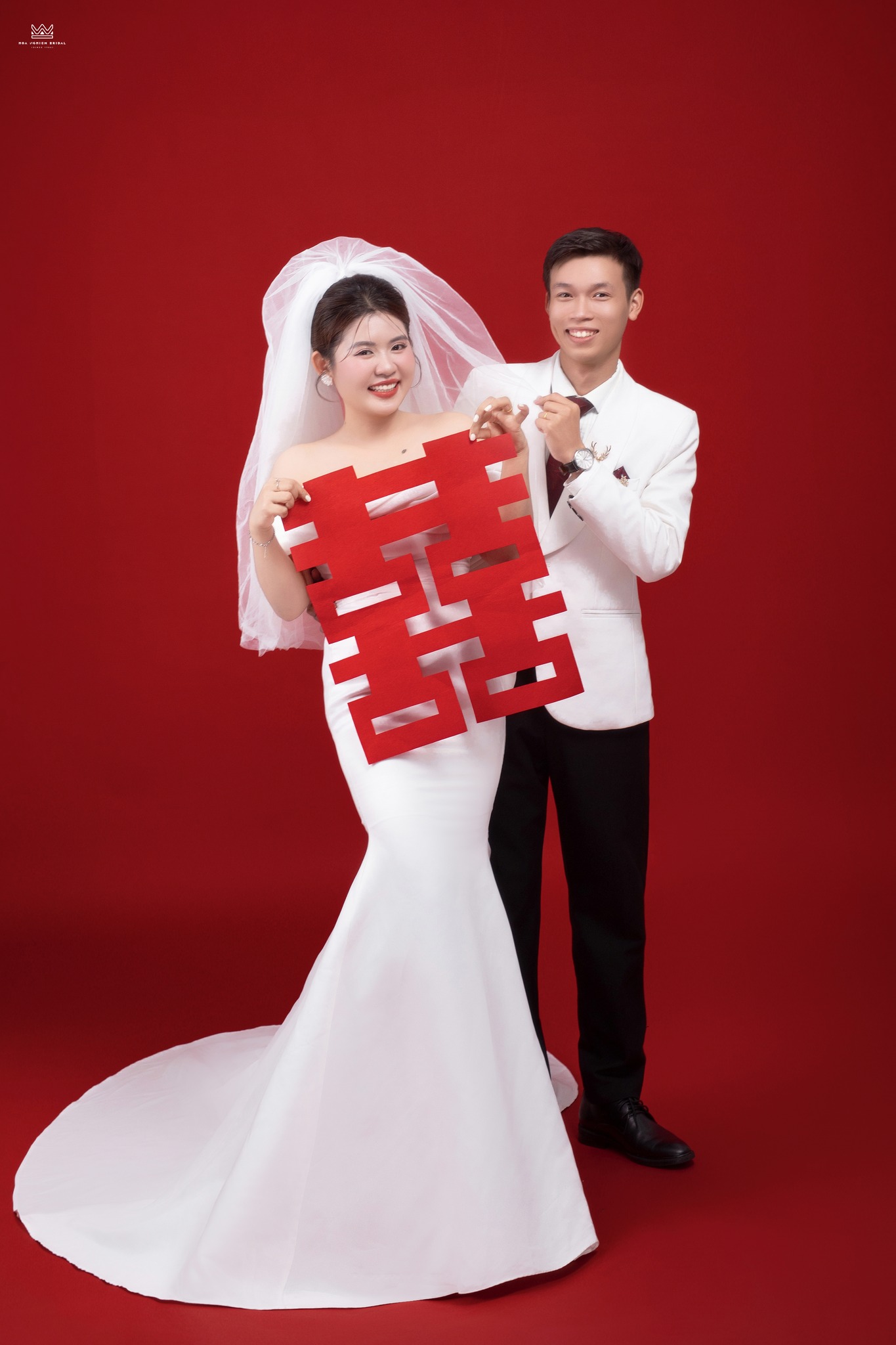 Ảnh cưới studio cô dâu chú rể cầm chữ song hỷ nền đỏ tại Huế
