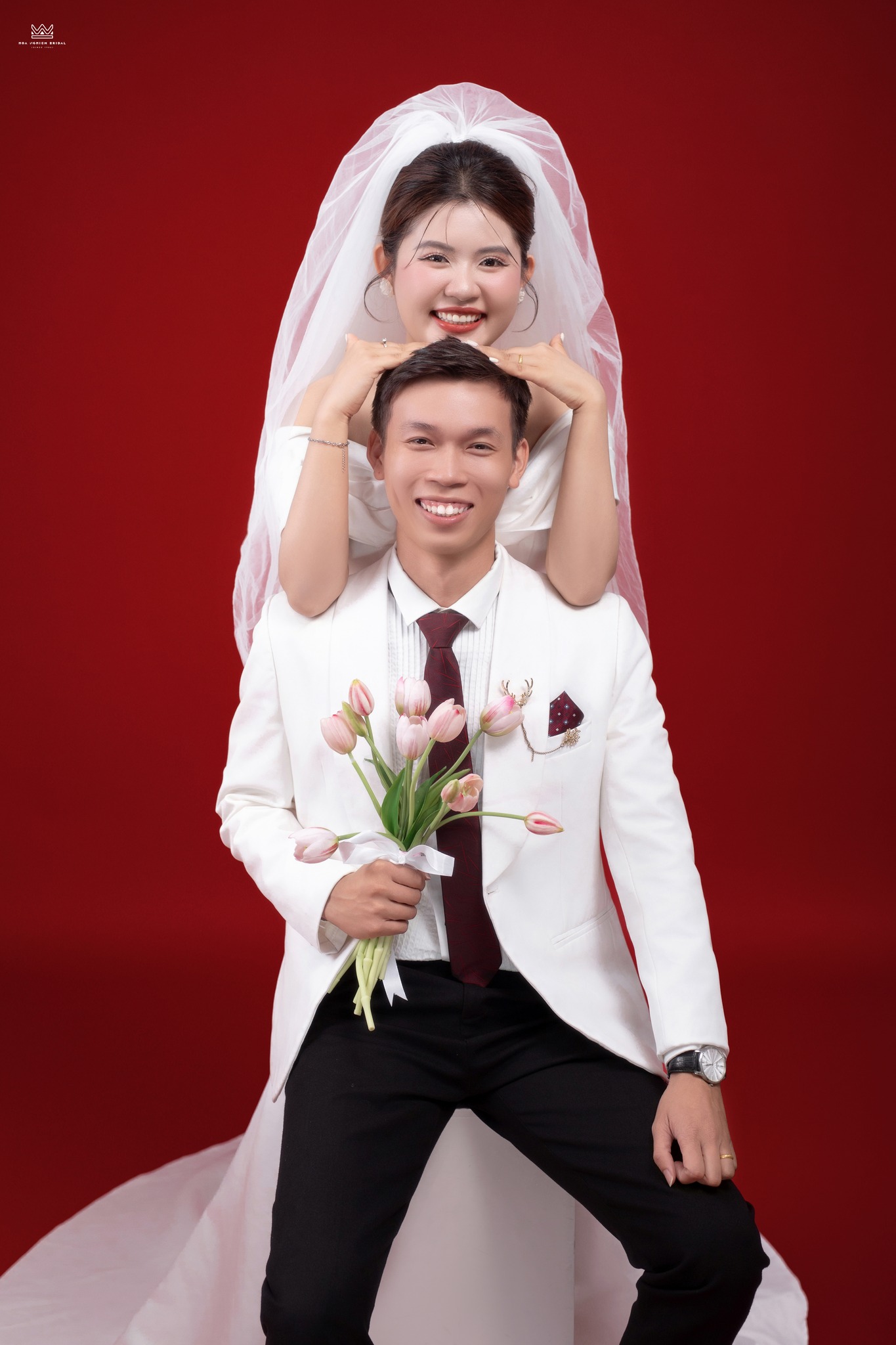 Ảnh cưới studio cô dâu ôm chú rể từ phía sau nền đỏ tại Huế