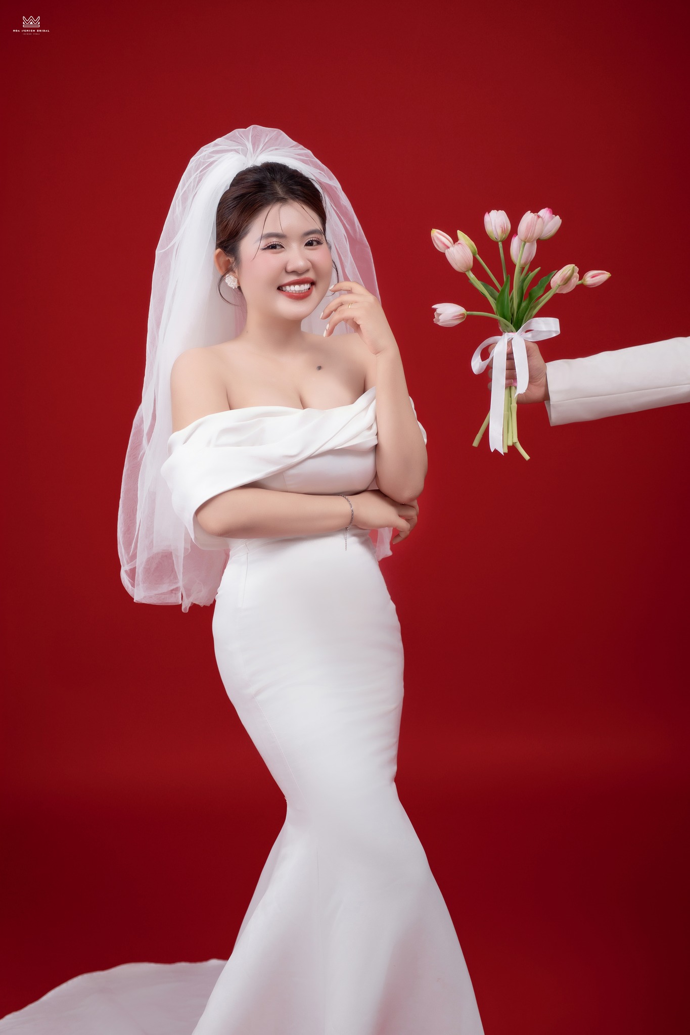 Cô dâu chụp ảnh cưới studio nhận hoa từ chú rể nền đỏ tại Huế