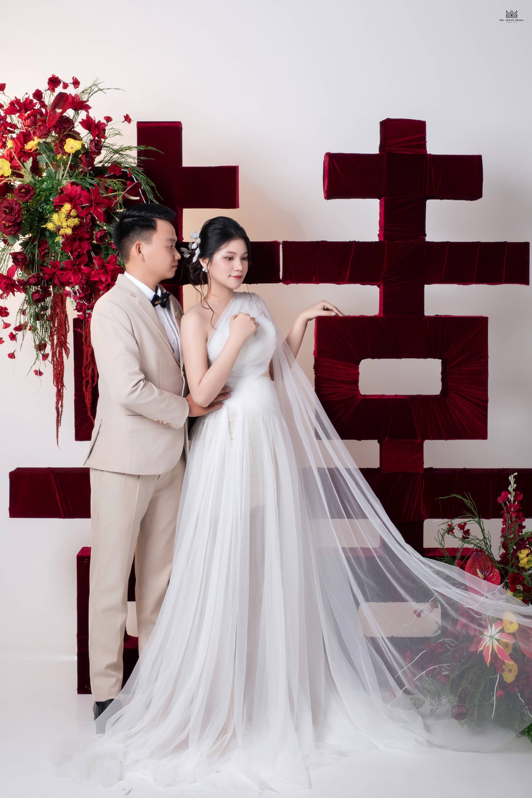 Chụp ảnh cưới phim trường tone đỏ truyền thống với background chữ hỷ nổi bật và concept hiện đại tại Hoa Nghiêm Bridal.