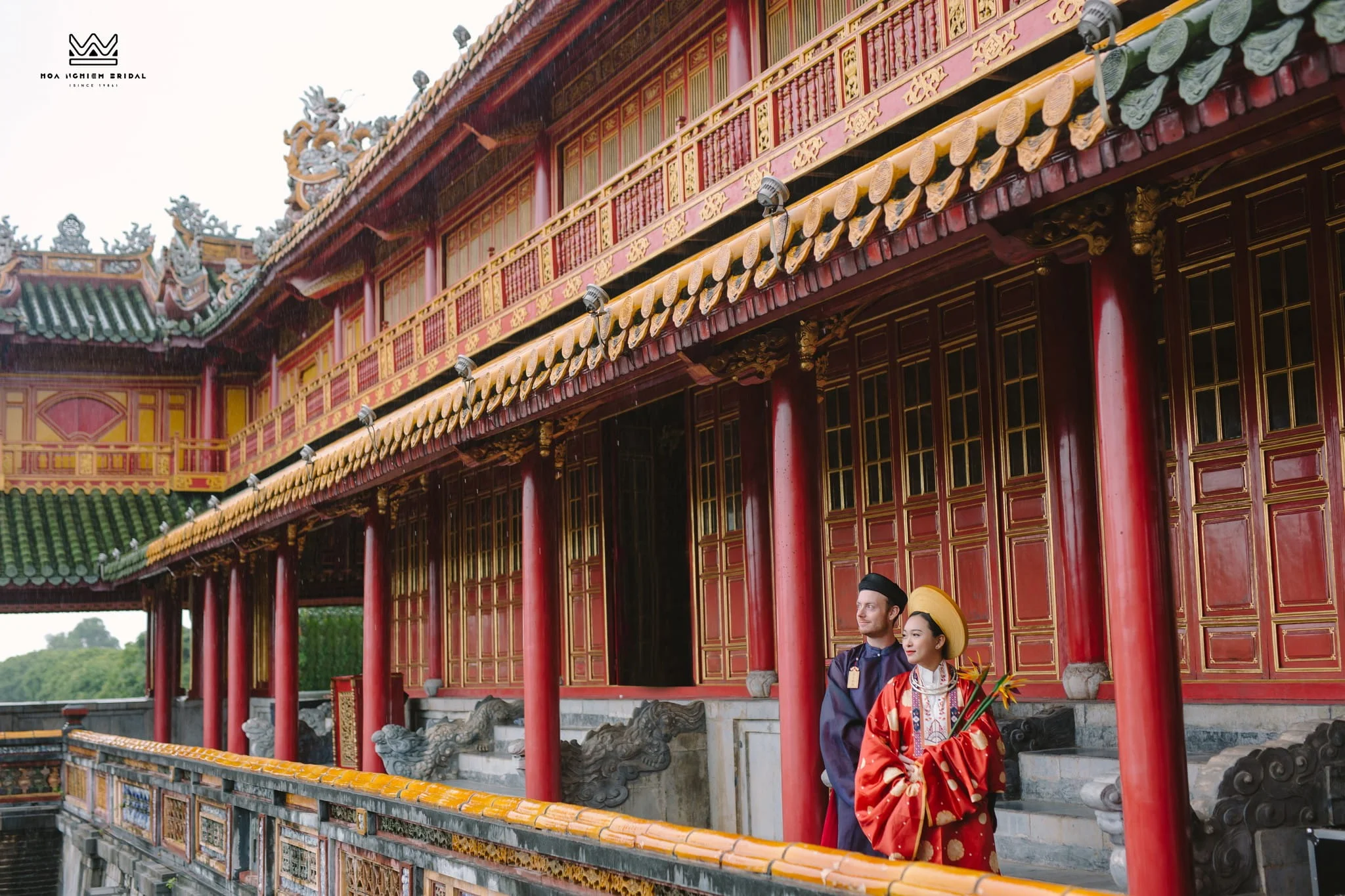 Foreign visitors wearing traditional Vietnamese costumes inside Hue Imperial City, enjoying a cultural photography session in the historic royal palace during a rainy day.